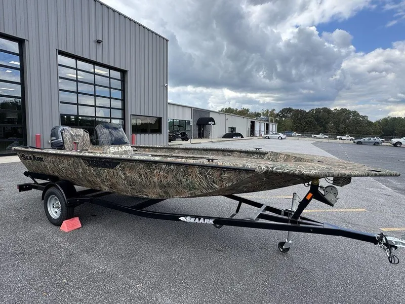 Slide: The Image of 2025 SeaArk Shadow 17 Side Console boat on trailer, camo design, parked outdoors. - 3