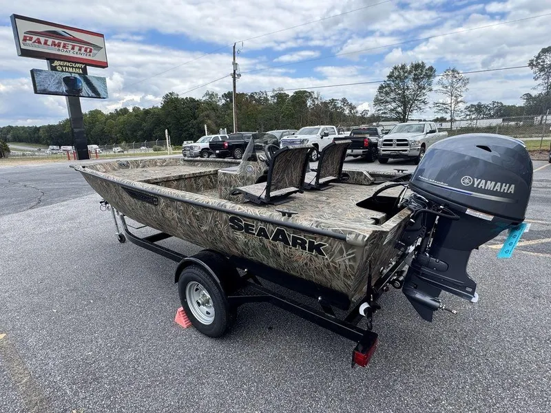 Slide: The Image of 2025 SeaArk Shadow 17 Side Console boat on trailer, camo design, parked outdoors. - 4