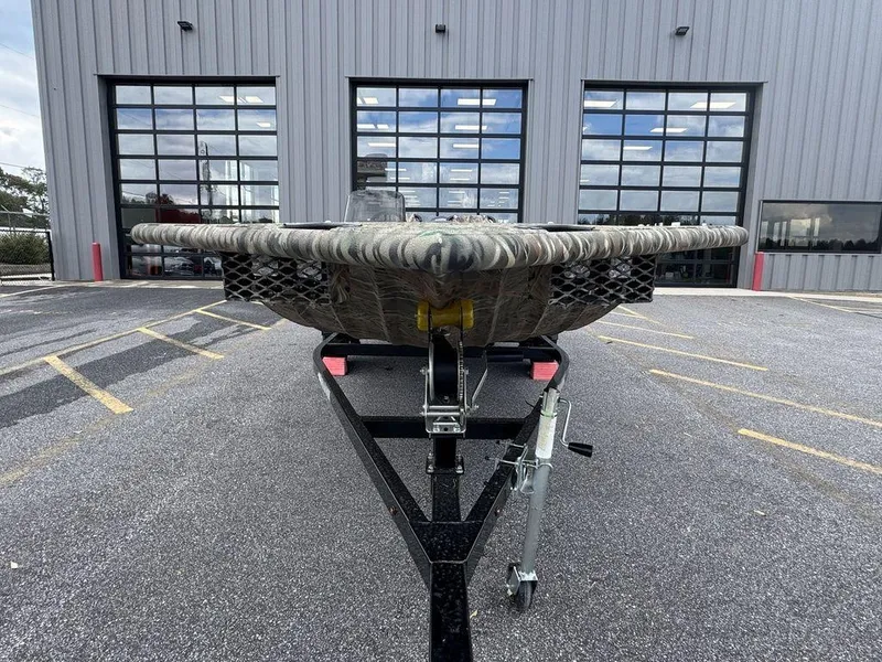 Slide: The Image of 2025 SeaArk Shadow 17 Side Console boat on trailer, camo design, parked outdoors. - 7