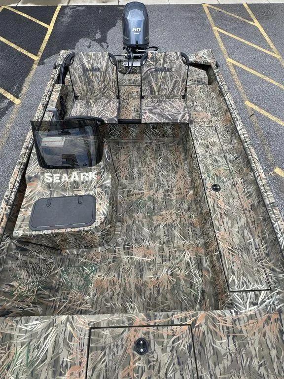 Slide: The Image of 2025 SeaArk Shadow 17 Side Console boat with camouflage design in a parking lot. - 15