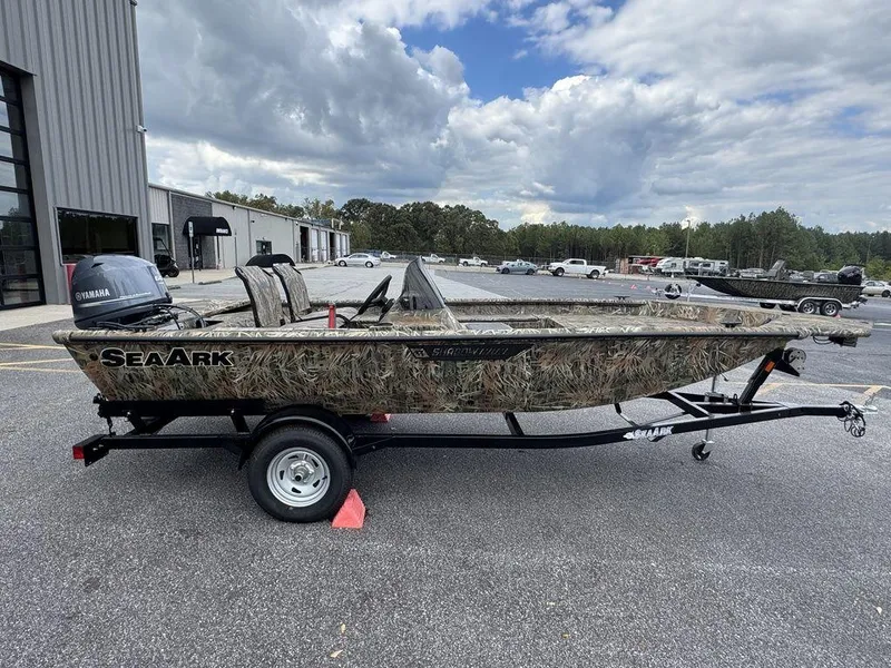 Slide: The Image of 2025 SeaArk Shadow 17 Side Console boat on trailer, camo design, parked outdoors. - 5