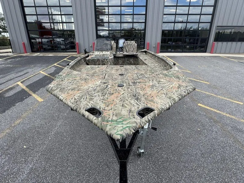 Slide: The Image of 2025 SeaArk Shadow 17 Side Console boat with camouflage design, parked outdoors. - 9