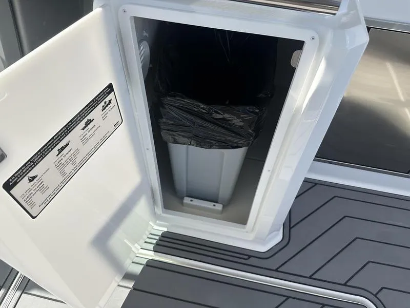 Slide: The Image of Cobalt R33 2023 boat interior with open storage compartment and trash bin. - 49