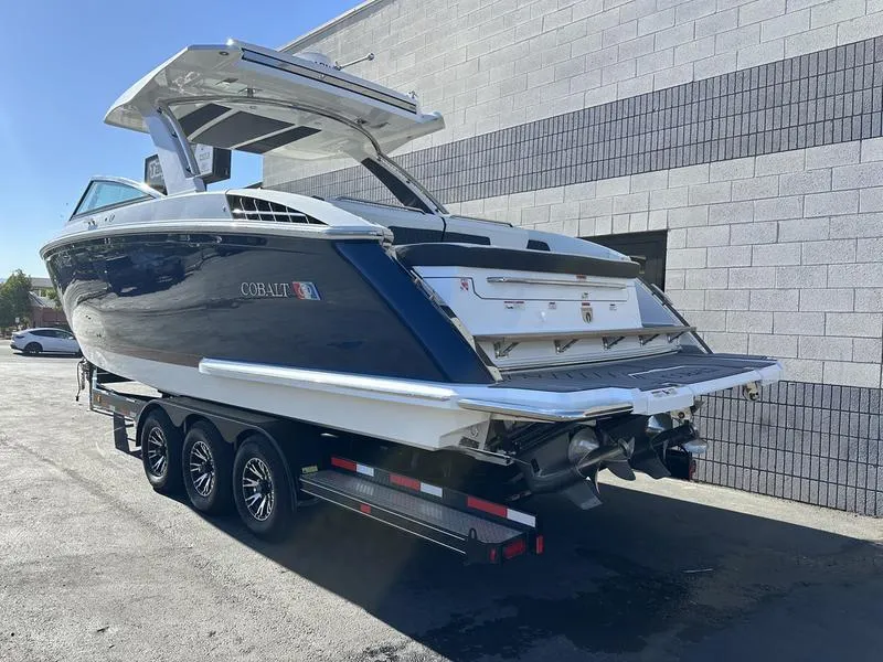 Slide: The Image of 2023 Cobalt R33 boat on trailer, parked near a brick wall. - 6