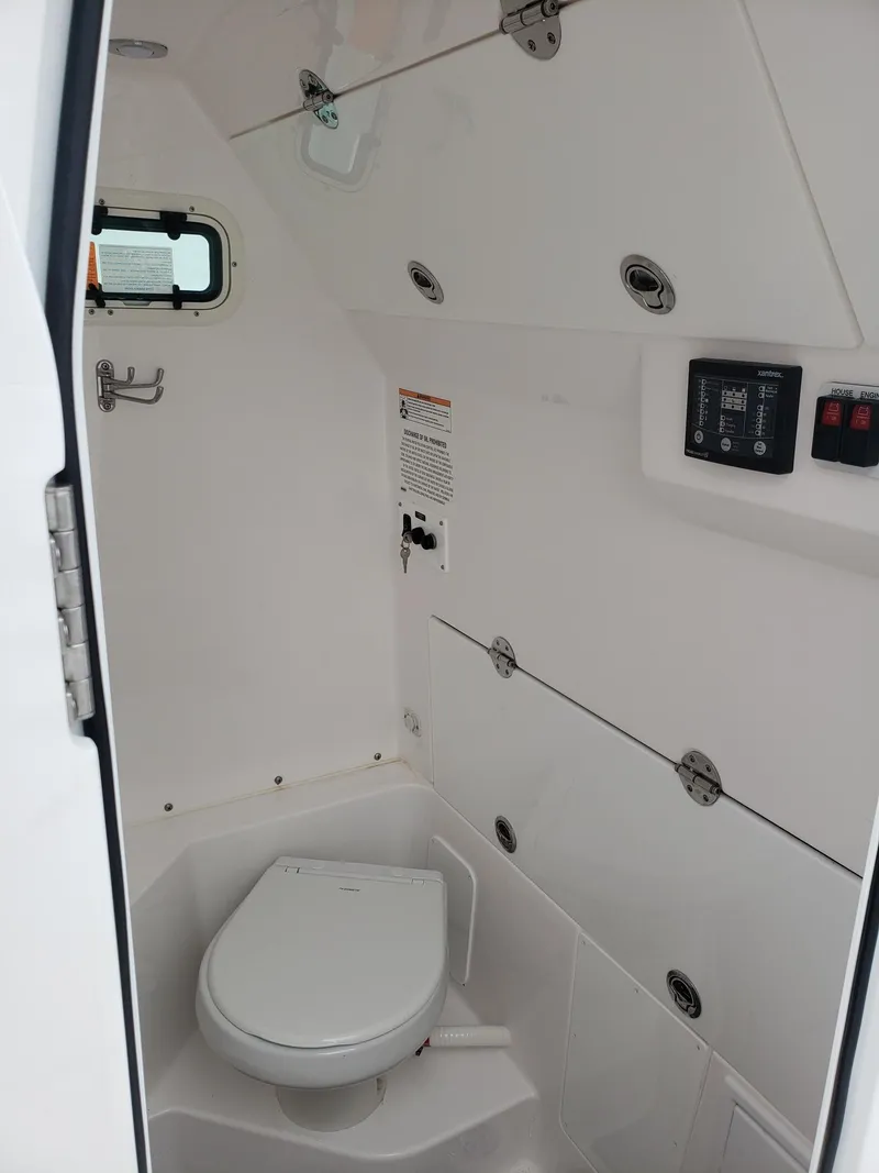 Slide: The Image of 2023 Everglades 285CC boat interior with compact marine toilet and control panel. - 29