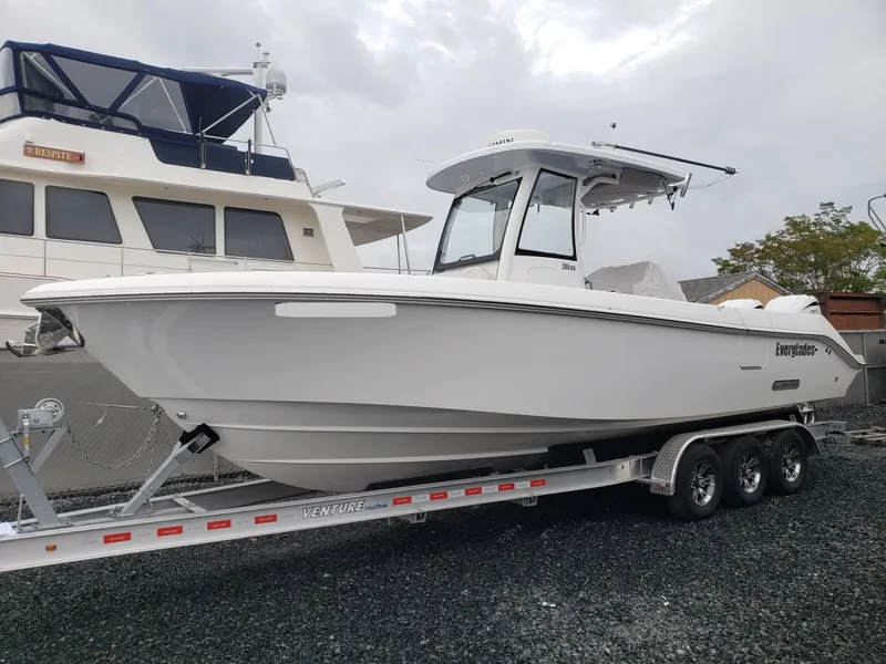 Slide: The Image of 2023 Everglades 285CC boat on trailer, parked beside another vessel. - 3