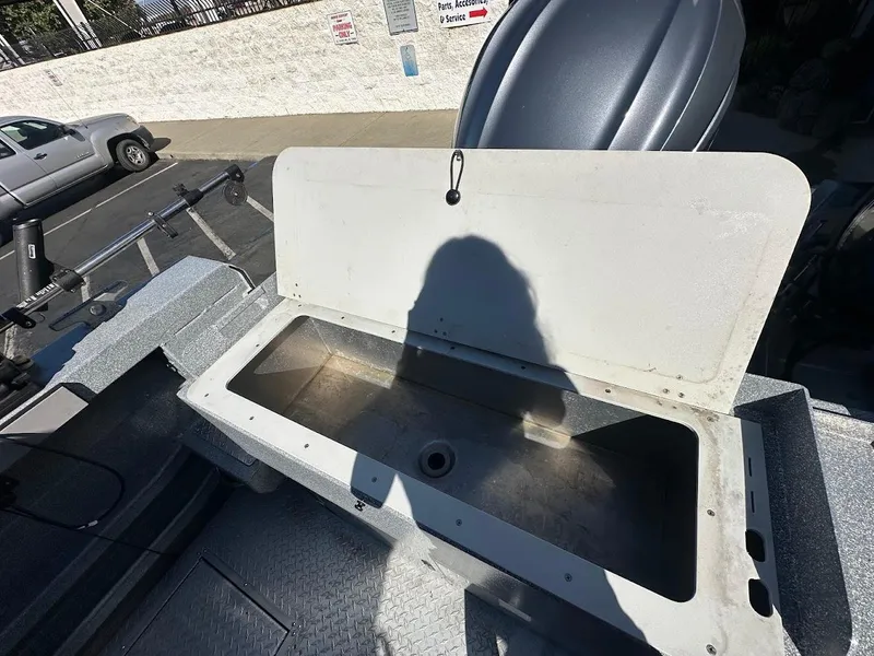 Slide: The Image of Open storage compartment on 2025 KingFisher 2225 Escape HT boat, with shadow and parking lot background. - 20