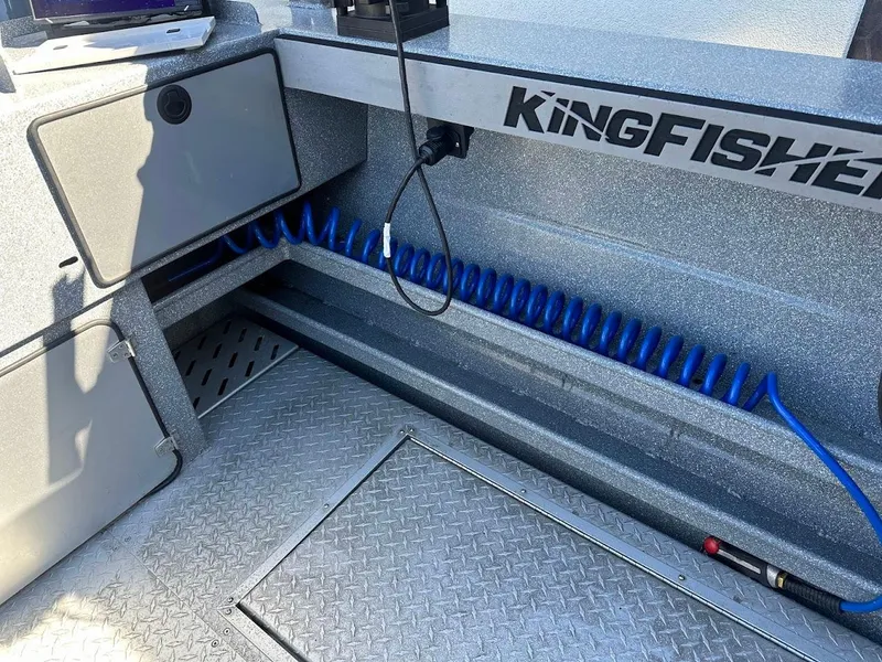 Slide: The Image of 2025 KingFisher 2225 Escape HT boat interior with storage and coiled blue hose. - 26