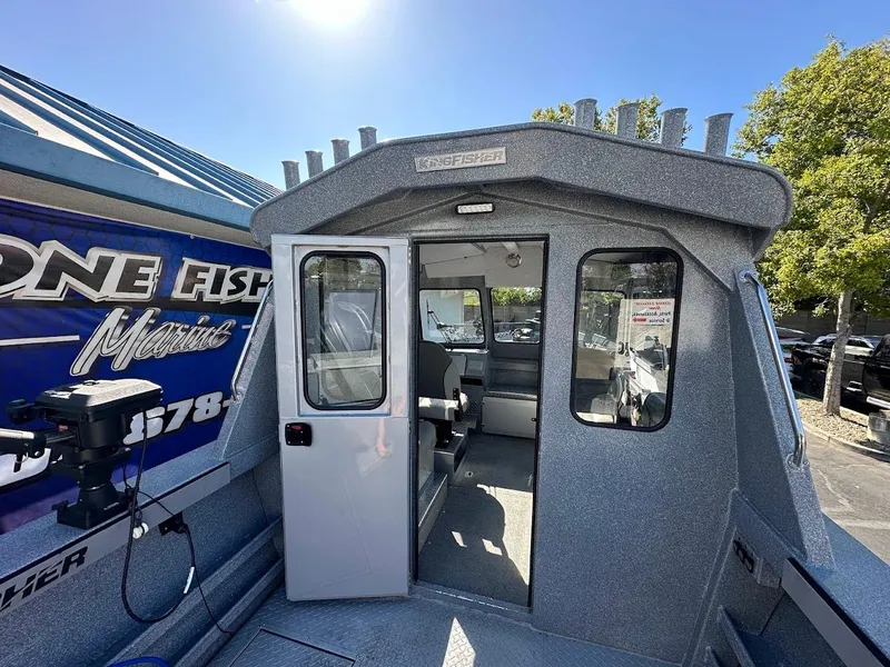 Slide: The Image of 2025 KingFisher 2225 Escape HT boat with open cabin door under clear blue sky. - 27