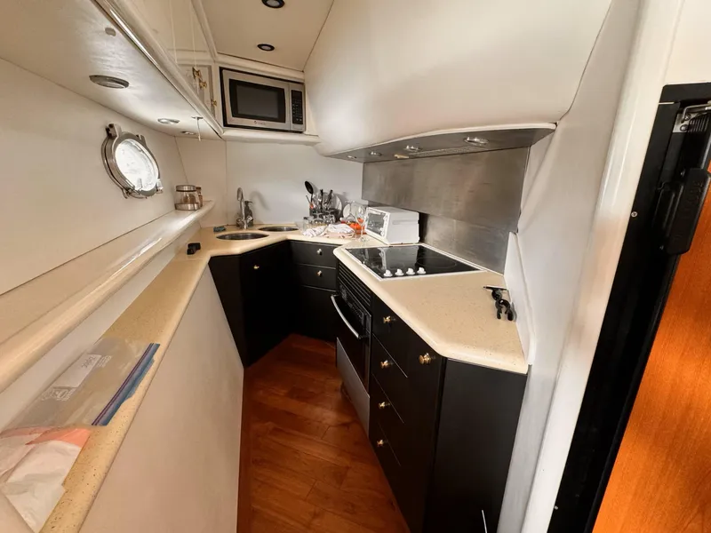 Slide: The Image of Compact kitchen in a 1995 Sunseeker MANHATTAN yacht with modern appliances and wood flooring. - 16