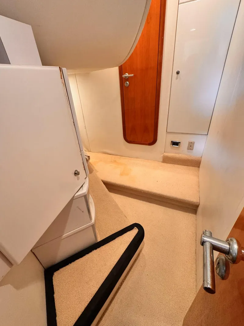 Slide: The Image of Interior of 1995 Sunseeker MANHATTAN yacht, featuring a compact, carpeted hallway and wooden door. - 18