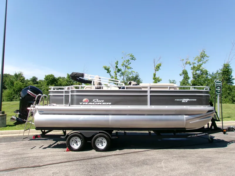 The Image of 2024 Sun Tracker Fishin' Barge 20 DLX pontoon boat on trailer, parked outdoors. - 0