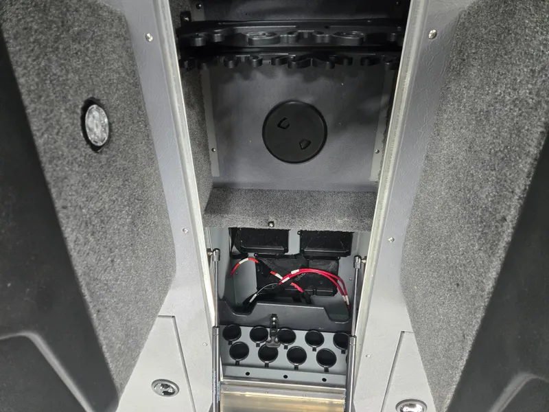 Slide: The Image of 2024 Princecraft Xpedition 200 boat interior storage compartment with wiring and cup holders. - 12