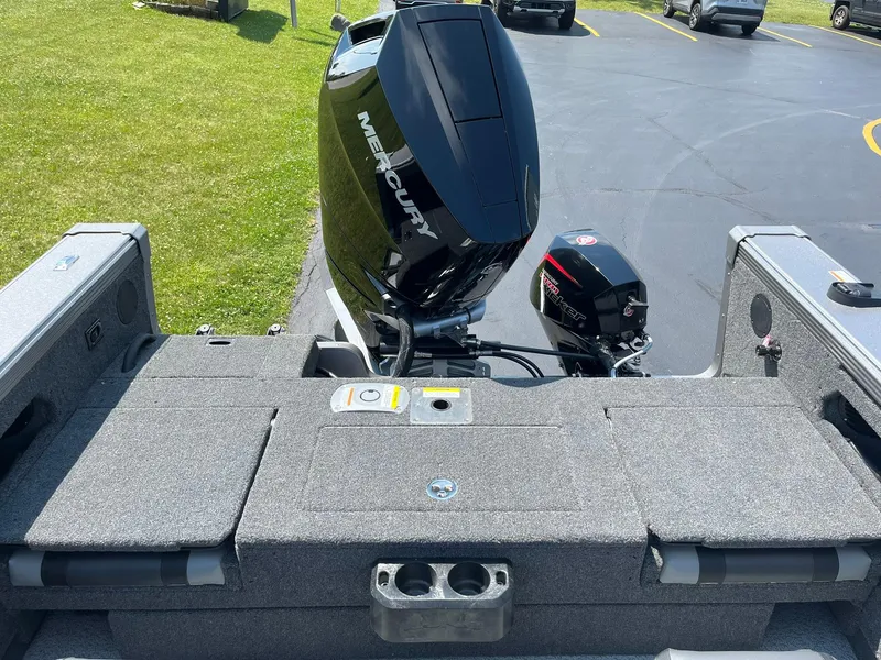 Slide: The Image of 2025 Lund 2275 Baron boat with Mercury outboard motor, parked on grass. - 14