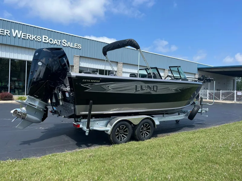 Slide: The Image of 2025 Lund 2275 Baron boat on trailer outside dealership. - 2