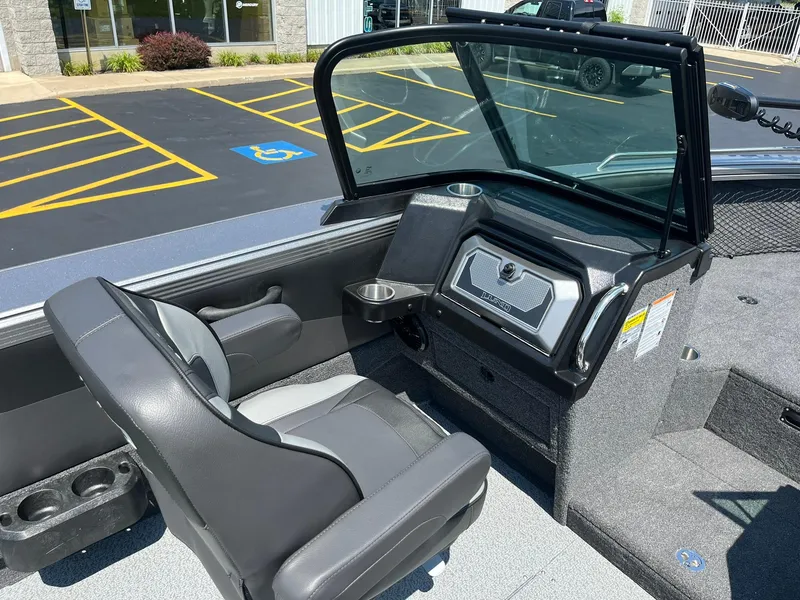 Slide: The Image of 2025 Lund 2275 Baron boat interior with seating and dashboard in a parking lot. - 23