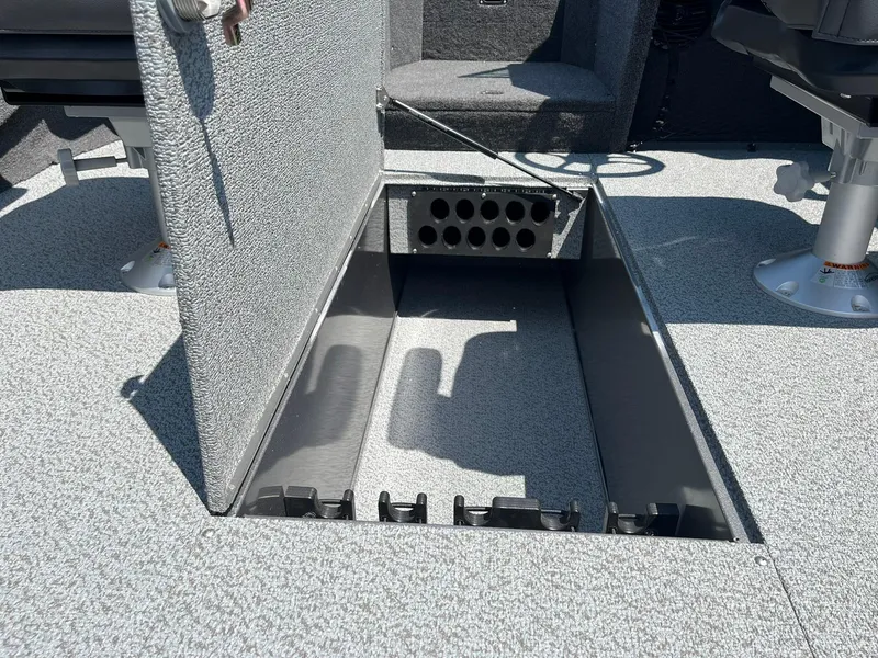 Slide: The Image of 2025 Lund 2275 Baron boat storage compartment with open hatch, gray interior. - 27