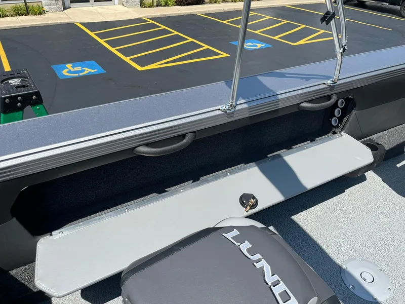 Slide: The Image of 2025 Lund 2275 Baron boat interior with storage compartment and parking lot view. - 37