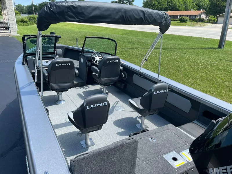 Slide: The Image of 2025 Lund 2275 Baron boat interior with seating and steering wheel, parked on grass. - 7