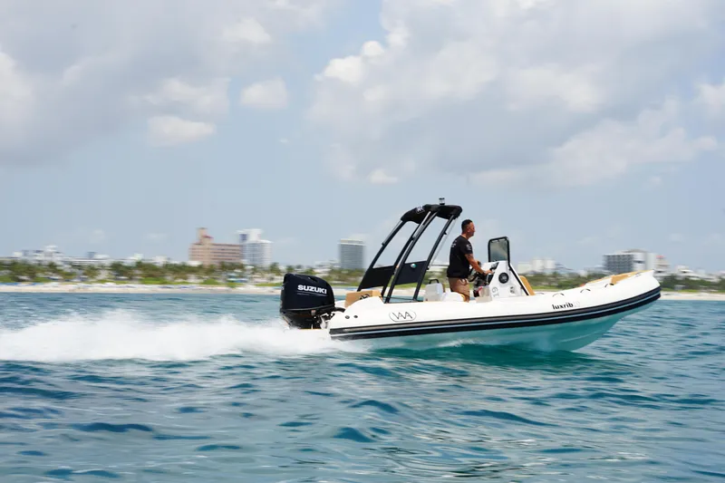 Slide: The Image of 2025 Aqvaboats Luxrib 19 speeding on water with cityscape background. - 0