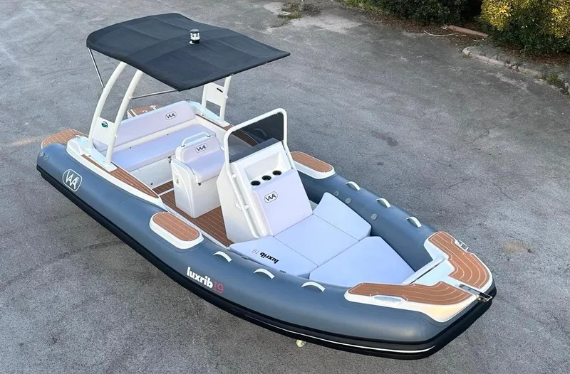 Slide: The Image of 2025 Aqvaboats luxrib 19 inflatable boat with canopy and seating on pavement. - 20