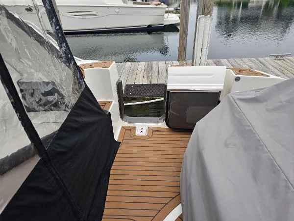 Slide: The Image of 2021 Tiara Sport 43 LE boat docked, featuring teak flooring and covered seating area. - 18