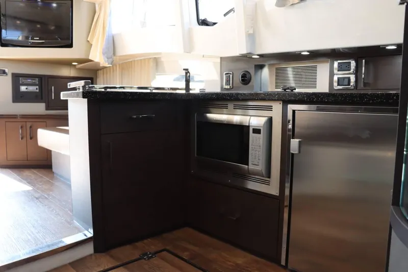 Slide: The Image of Modern kitchen area in 2014 Marquis 42 Sport Bridge yacht with microwave and stainless steel appliances. - 23