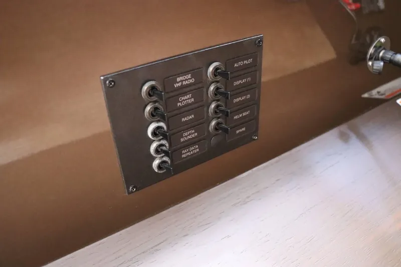 Slide: The Image of Control panel of a 2014 Marquis 42 Sport Bridge yacht with labeled switches. - 46
