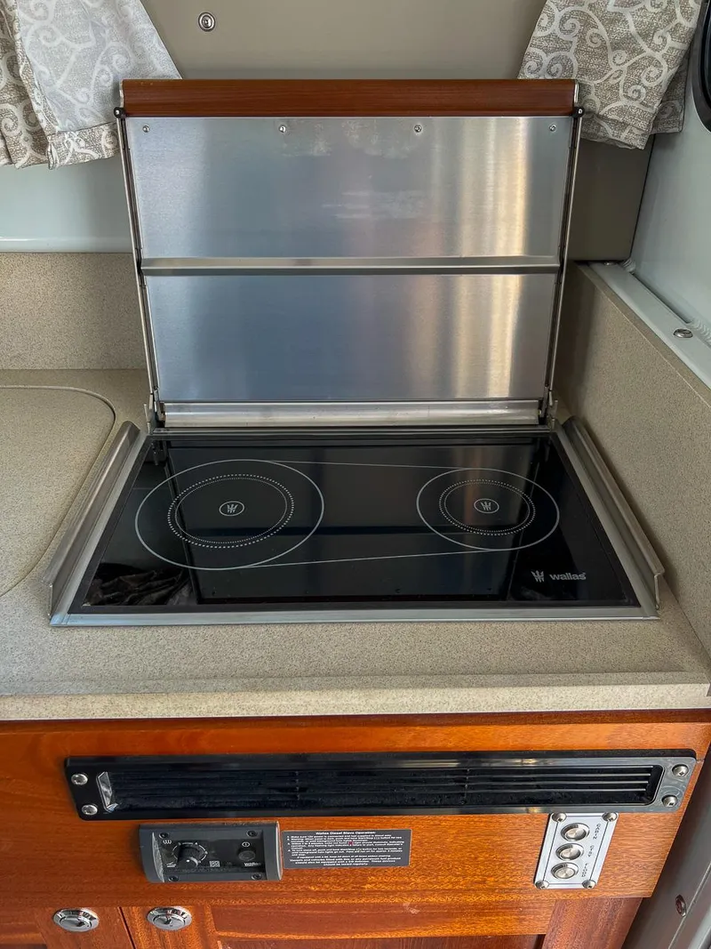 Slide: The Image of 2022 Hewescraft 290 Adventure kitchen with electric stovetop and wooden cabinetry. - 16