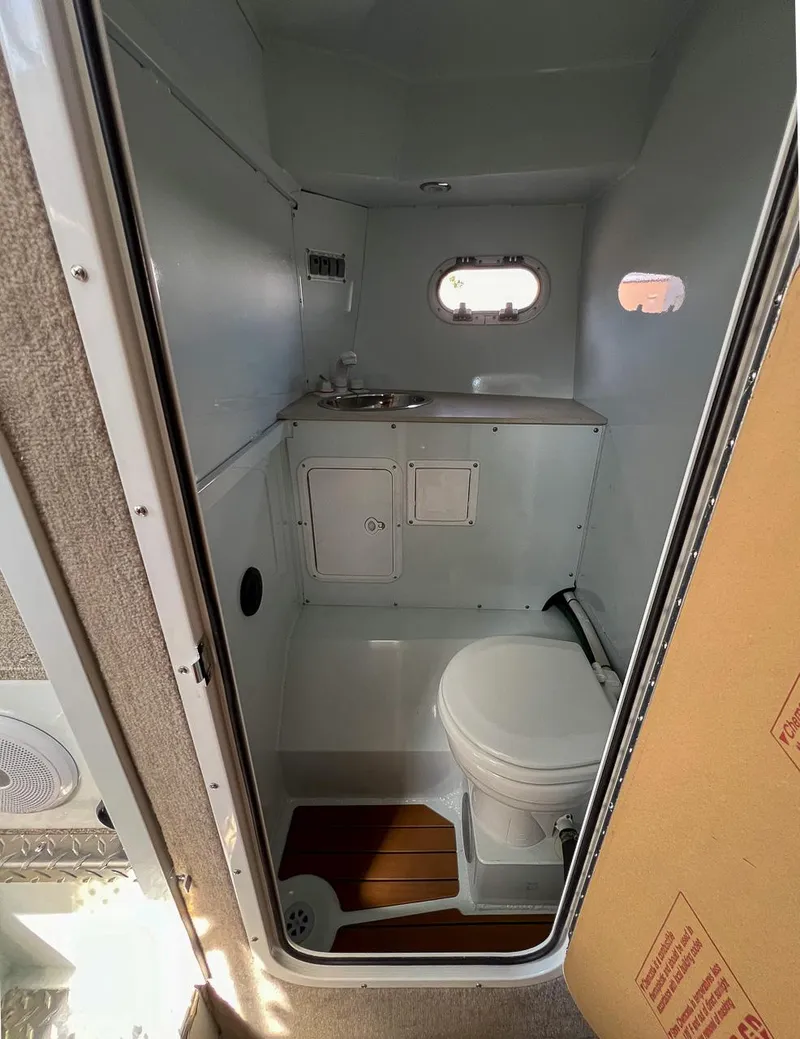 Slide: The Image of Compact bathroom in 2022 Hewescraft 290 Adventure boat with toilet, sink, and small window. - 9