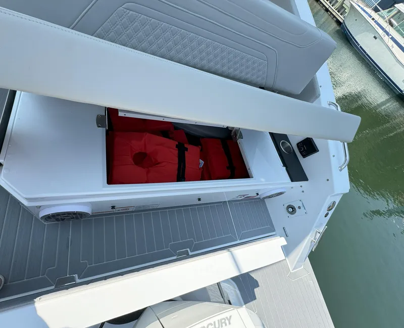 Slide: The Image of 2025 Cruisers Yachts 34 GLS Outboard with open storage compartment and red life jacket. - 18