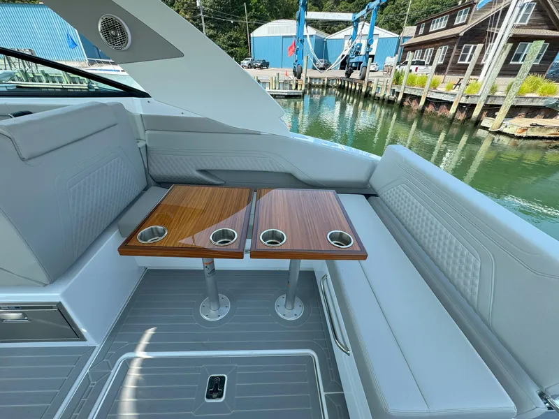 Slide: The Image of 2025 Cruisers Yachts 34 GLS Outboard interior with seating and wooden tables by the water. - 25