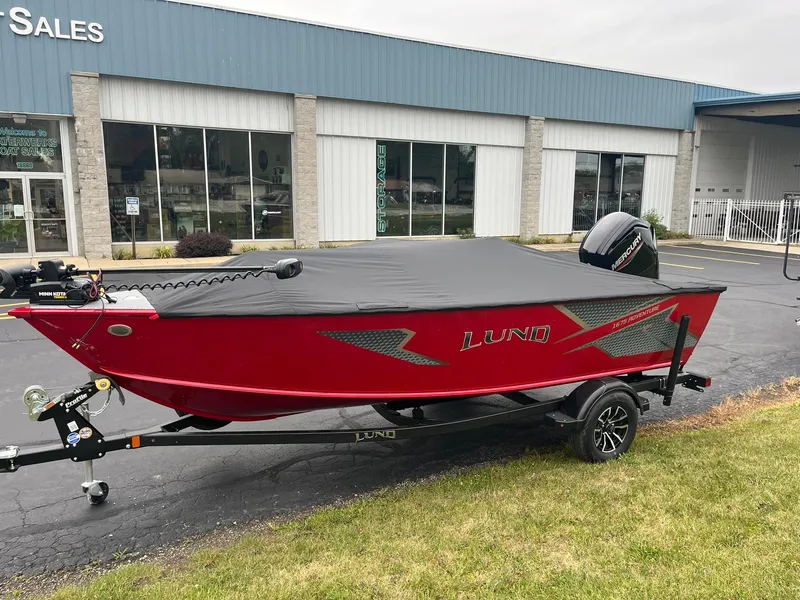 Slide: The Image of 2025 Lund 1675 Adventure SS boat, red, on trailer outside dealership. - 16