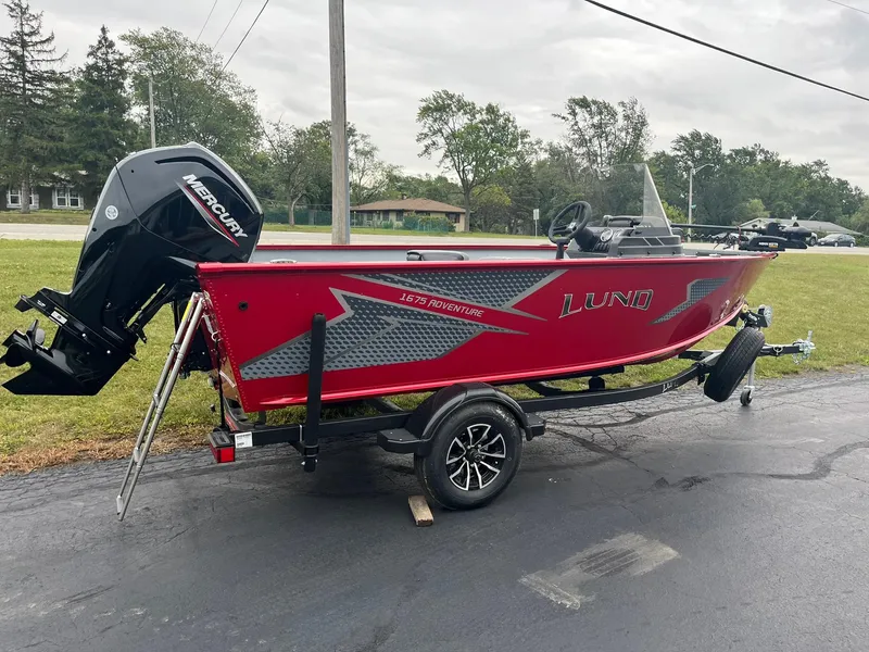 Slide: The Image of 2025 Lund 1675 Adventure SS boat on trailer, red exterior, parked outdoors. - 3