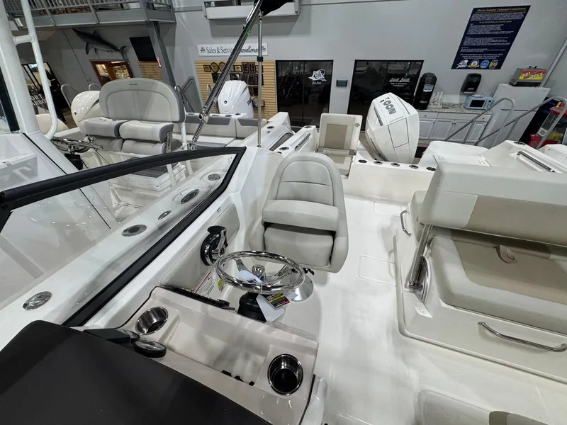 Slide: The Image of 2025 Boston Whaler 210 Vantage interior with seating and steering wheel in showroom. - 9