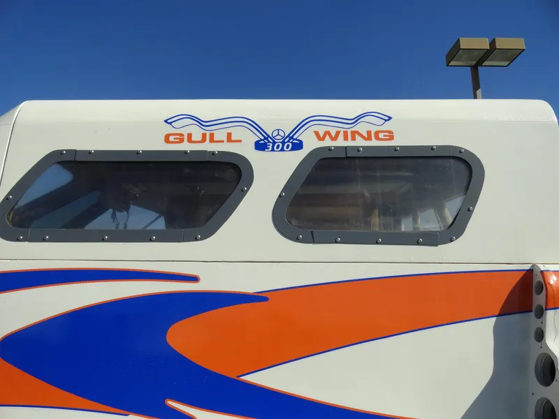 Slide: The Image of 1996 Hallett Party Cruiser Gull Wing 300 boat with blue and orange design. - 6