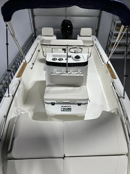 Slide: The Image of 2025 Boston Whaler 190 Montauk boat interior with console and seating, under a canopy. - 15