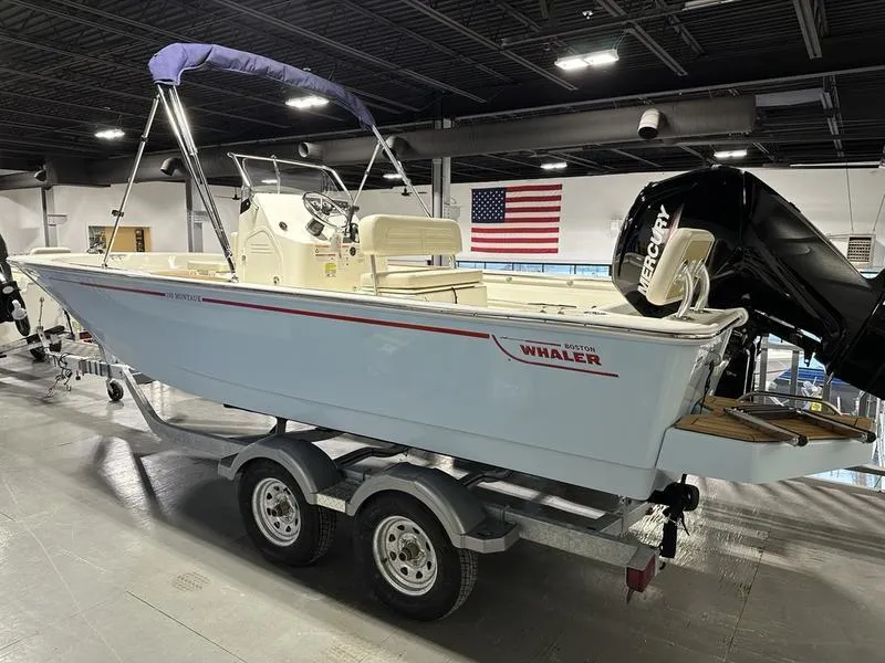 Slide: The Image of 2025 Boston Whaler 190 Montauk boat on trailer, indoors, with American flag in background. - 4