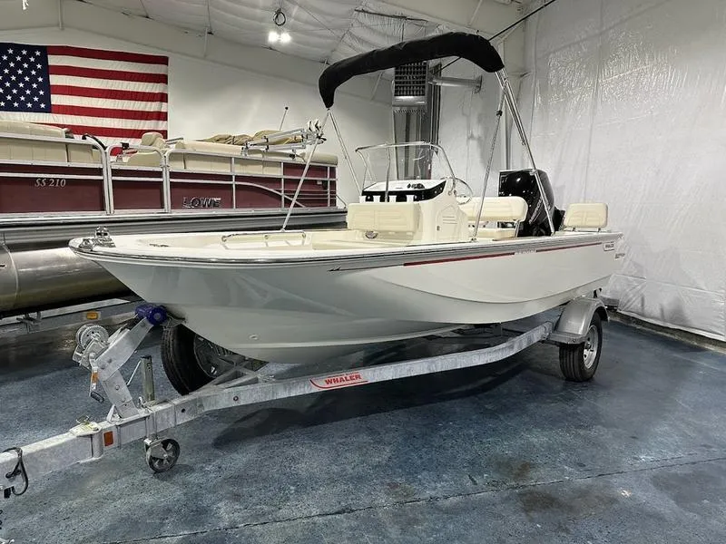 Slide: The Image of 2025 Boston Whaler 170 Montauk boat on trailer in showroom with American flag. - 1