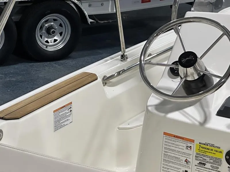 Slide: The Image of 2025 Boston Whaler 170 Montauk boat interior with steering wheel and safety labels. - 7