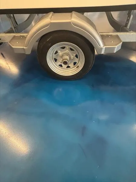 Slide: The Image of 2025 Boston Whaler 130 Super Sport trailer wheel on blue floor. - 2