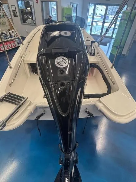 Slide: The Image of 2025 Boston Whaler 130 Super Sport boat with powerful outboard motor in showroom. - 6
