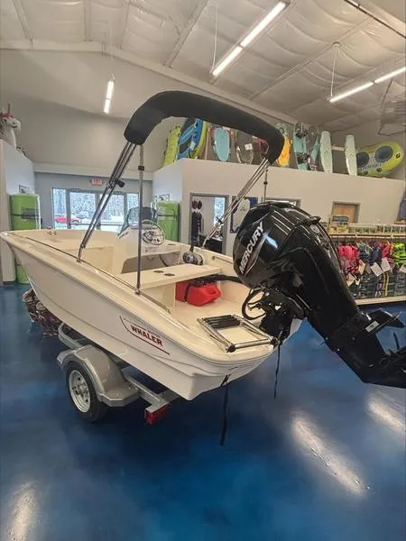 Slide: The Image of 2025 Boston Whaler 130 Super Sport boat displayed indoors with Mercury engine. - 7