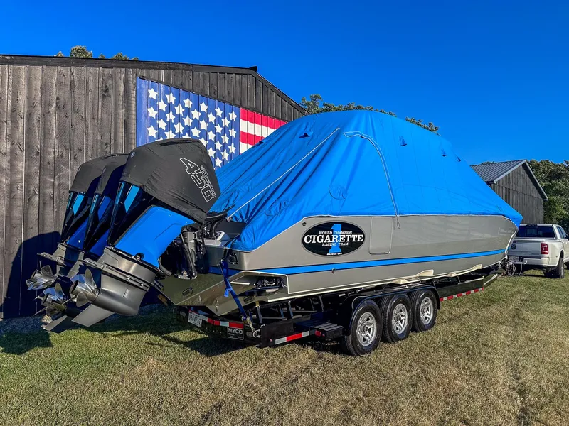 Slide: The Image of 2021 Cigarette 39 GTS boat with blue cover on trailer, parked near American flag mural. - 19