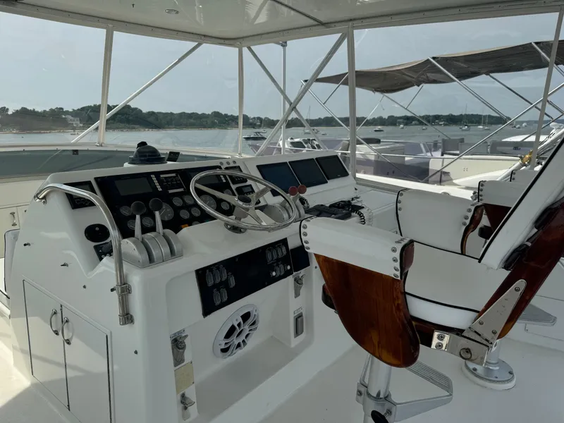 Slide: The Image of Helm of 1994 Hatteras 54 Convertible yacht with controls and seating, docked in marina. - 18