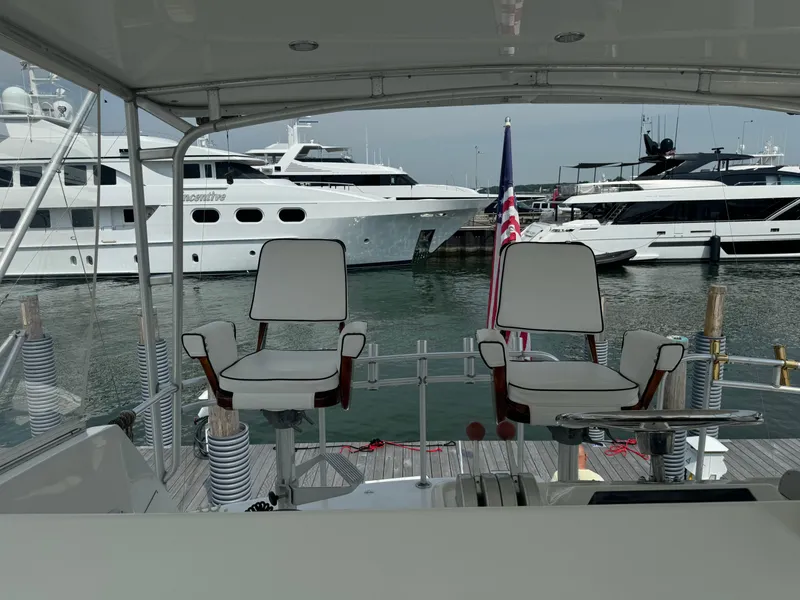 Slide: The Image of 1994 Hatteras 54 Convertible yacht with two helm chairs, docked in a marina. - 20