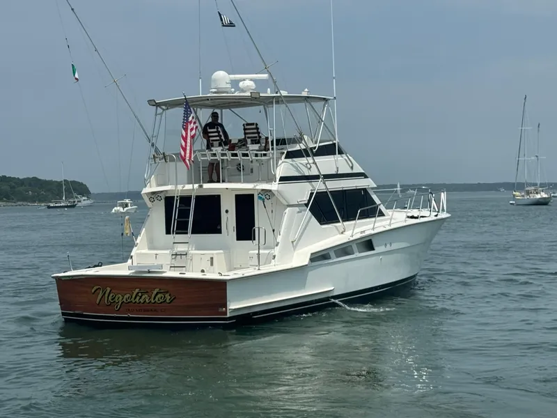 Slide: The Image of 1994 Hatteras 54 Convertible yacht on calm water, rear view with American flag. - 3
