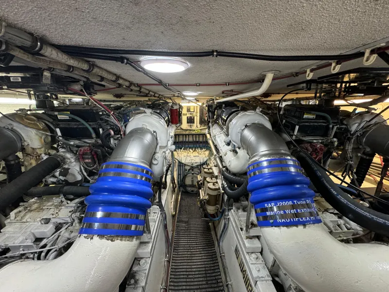 Slide: The Image of Engine room of a 1994 Hatteras 54 Convertible yacht, featuring dual engines and blue exhaust hoses. - 42