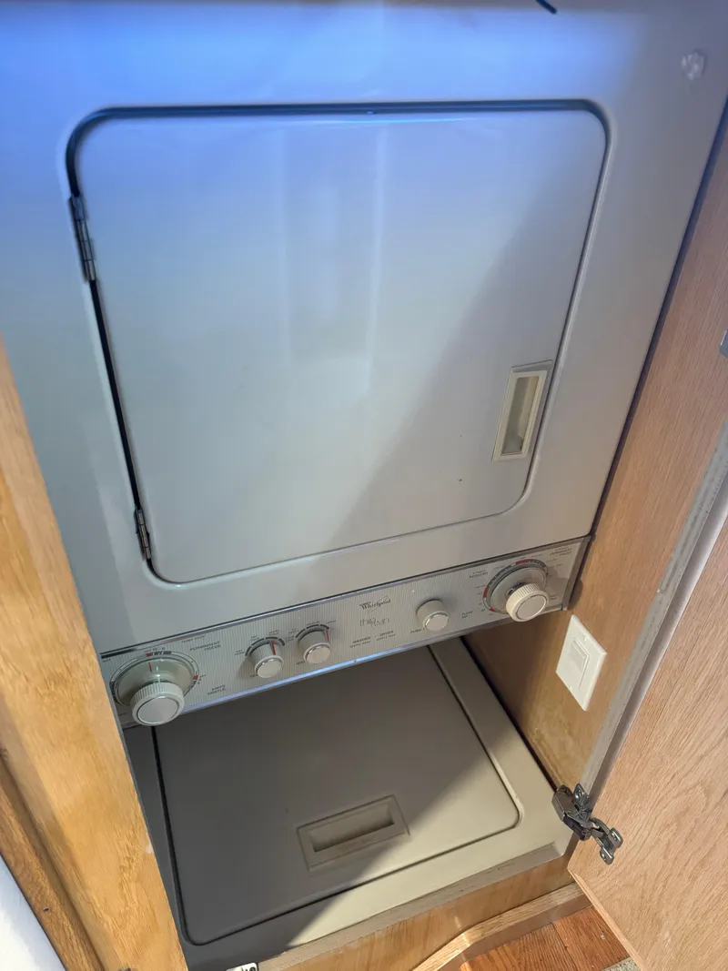 Slide: The Image of Laundry unit inside 1994 Hatteras 54 Convertible yacht, featuring a compact washer and dryer. - 44