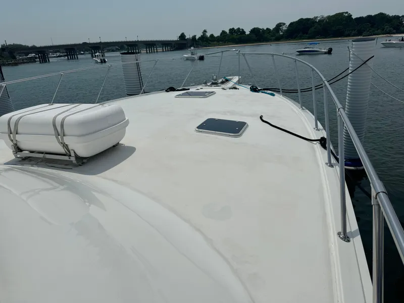 Slide: The Image of 1994 Hatteras 54 Convertible yacht deck with railing and hatch, docked in a serene marina. - 9